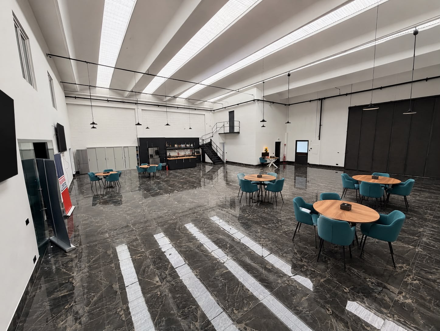 Hall eventi con tavoli, bar e area palco